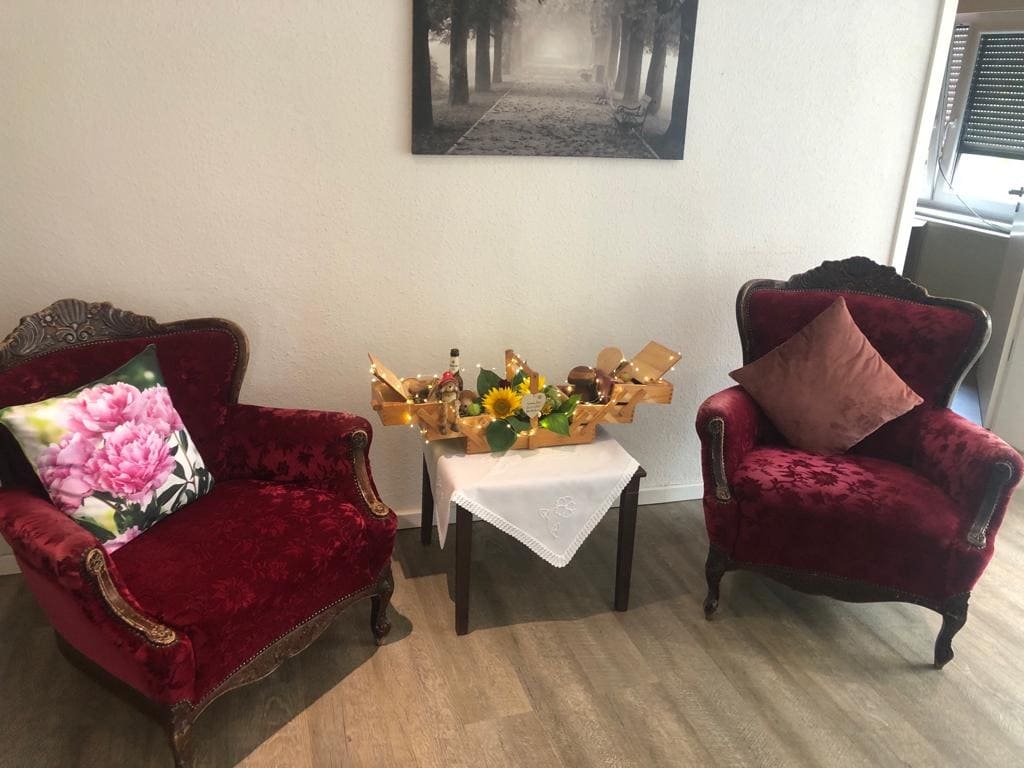 Sitzecke der Tagespflege mit gepolsterten Sesseln und einem Tisch mit Blumen