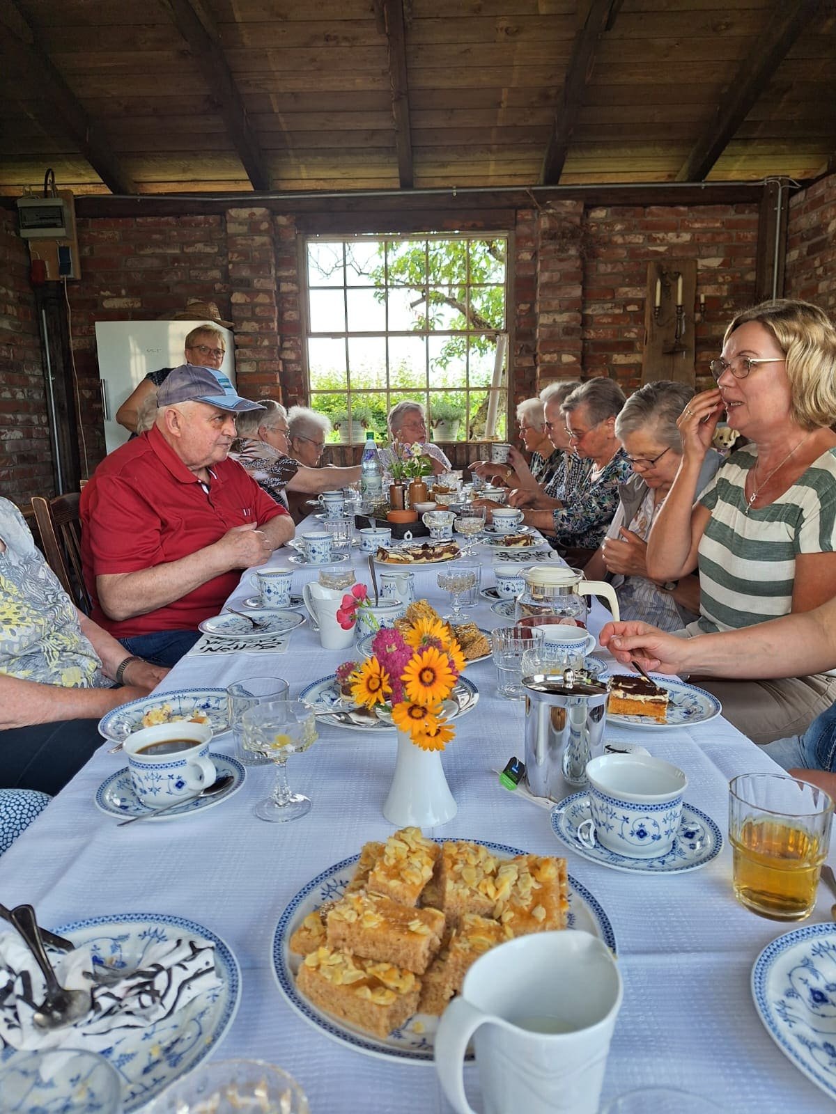 Lange gedeckte Tafel mit Gästen beim gemeinsamen Essen